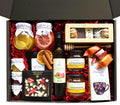 Geschenkkorb mit Honig Tee Schokolade Konfitüre Sirup Nüsse im dekorativen Korb voller Genuss