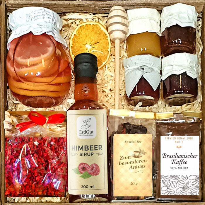 Geschenkkorb mit Honig Tee Schokolade Konfitüre Sirup und Nüssen im dekorativen Genusskorb