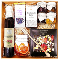 Geschenkkorb mit Tee Honig Schokolade Sirup Zitrone und Kaffee im dekorativen Korb voller Genuss