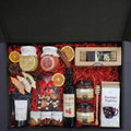 Geschenkkorb mit Honig Tee Schokolade Konfitüre Nüsse Sirup im dekorativen Korb voller Genussmomente