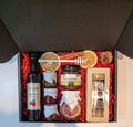Geschenkkorb mit Honig Tee Schokolade Konfitüre Sirup und Nüssen im dekorativen Korb voller Genuss