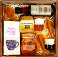 Geschenkkorb mit Honig Tee Schokolade Konfitüre und Sirup im dekorativen Genusskorb