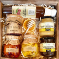 Geschenkkorb mit Honig Tee Schokolade Konfitüre Sirup und Nüssen im dekorativen Korb voller Genuss