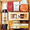 Geschenkkorb mit Honig Tee Schokolade Konfitüre Sirup und Nüssen im dekorativen Genusskorb